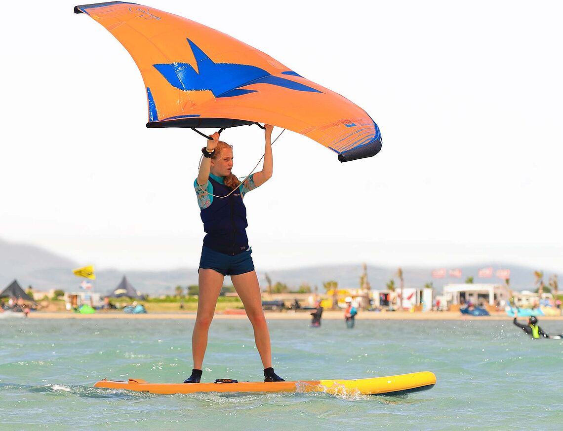 Wingfoiling at KBC Sicily Lo Stagnone - Woman with wing on SUP board in turquoise water, Sicily kite spot water sports