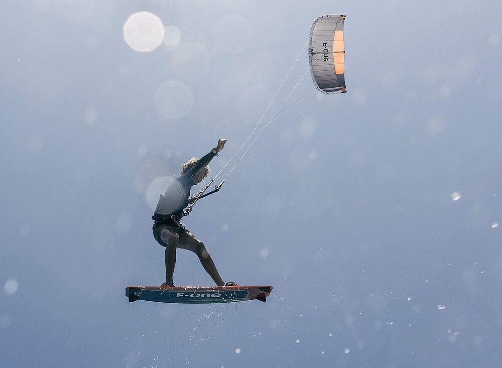 Kitesurf Holland001 kitesurfing in der Luft mit F-one Board und Kite gegen blauen Himmel - Kiteboarding Wassersport