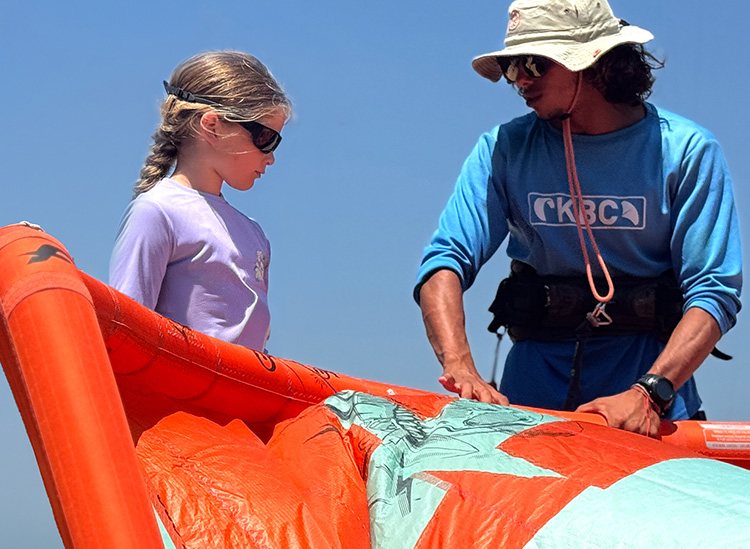 Kitesurfen Kinder-Kitekurs: Kiteschülerin und Lehrerin beim Kite-Setup am Strand -Wassersport für Kids lernen am KBC El gouna