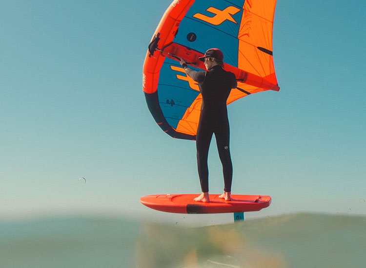 Kitesurfista con aquilone arancione-blu su tavola al Kiteboarding Club KBC Sizilien - condizioni perfette