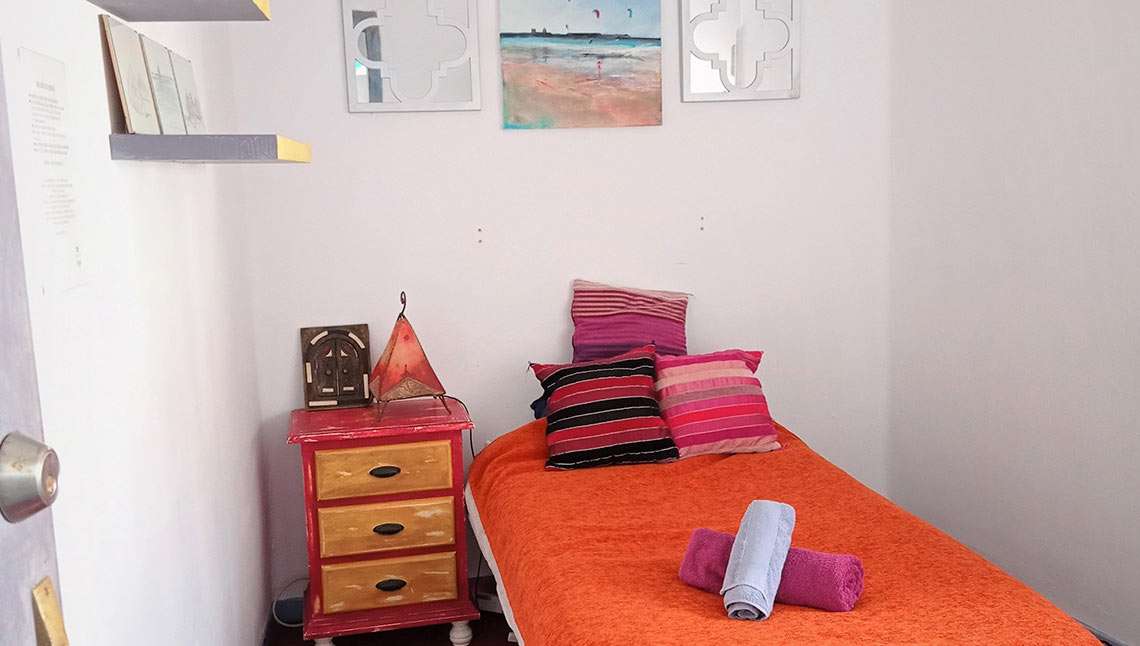 High Flyers Balneario Gästezimmer mit Einzelbett und bunten Kissen bei KBC Tarifa Kitesurfschule in Spanien
