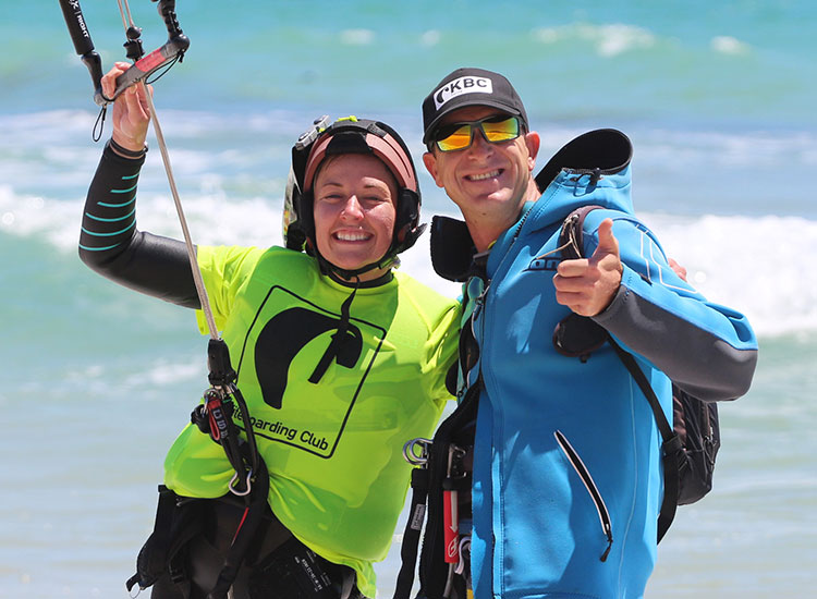 Studente kitesurf felice con istruttore sulla spiaggia dopo lezione riuscita al Kiteboarding Club KBC Tarifa