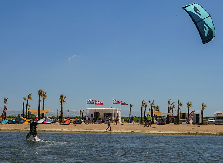 Sizilien Kiteurlaub: Kitesurfer in spiaggia con aquilone turchese, palme e scuola kite - destinazione kitesurf perfetta