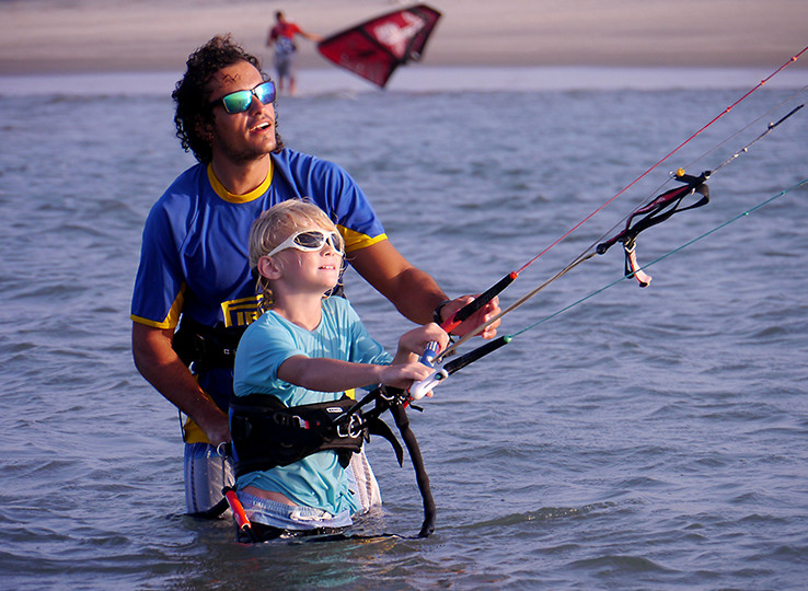 Kiteboarding lesson: instructor teaching child kitesurfing in water - beach water sports travel destination