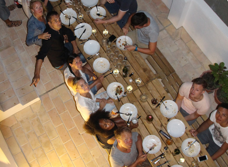 Kitesurfing group enjoying dinner together on terrace - perfect end to a kiteboarding day at beach travel destination